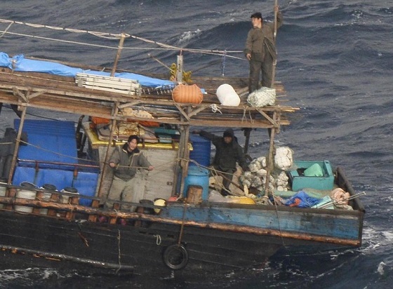 北海道松前町沖で発見された国籍不明の木造船。乗員の姿も見える＝２０１７年１１月２９日午前１１時６分、本社機「希望」から