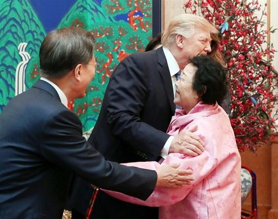韓国大統領府での夕食会で、抱き合ってあいさつするトランプ米大統領（中央）と元慰安婦の李容洙さん。左は文在寅大統領＝７日、ソウル（聯合＝共同）